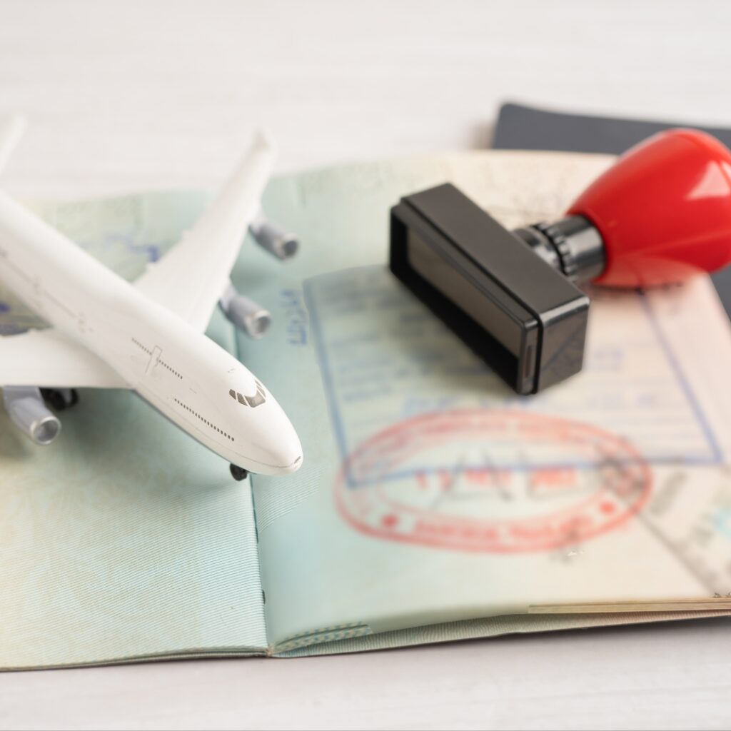 Model airplane on an open passport with travel stamps and a rubber stamp, symbolizing international travel.
